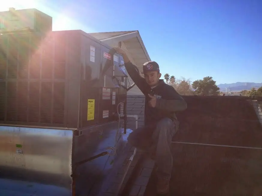 HVAC technician performing AC Tune-Up on a rooftop unit in Bettendorf
