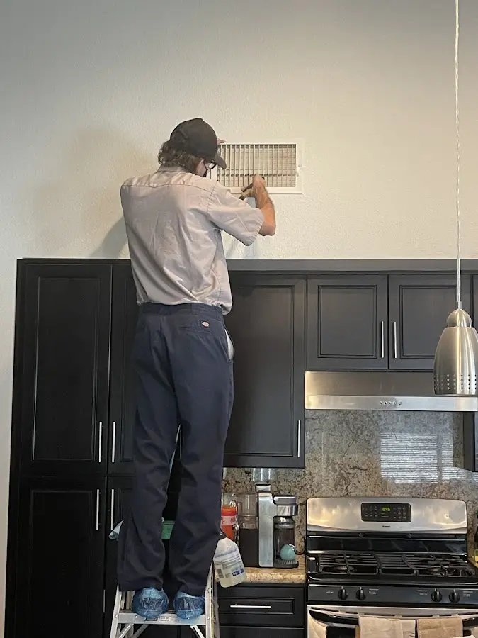 Technician inspecting an air vent during HVAC service in Bettendorf